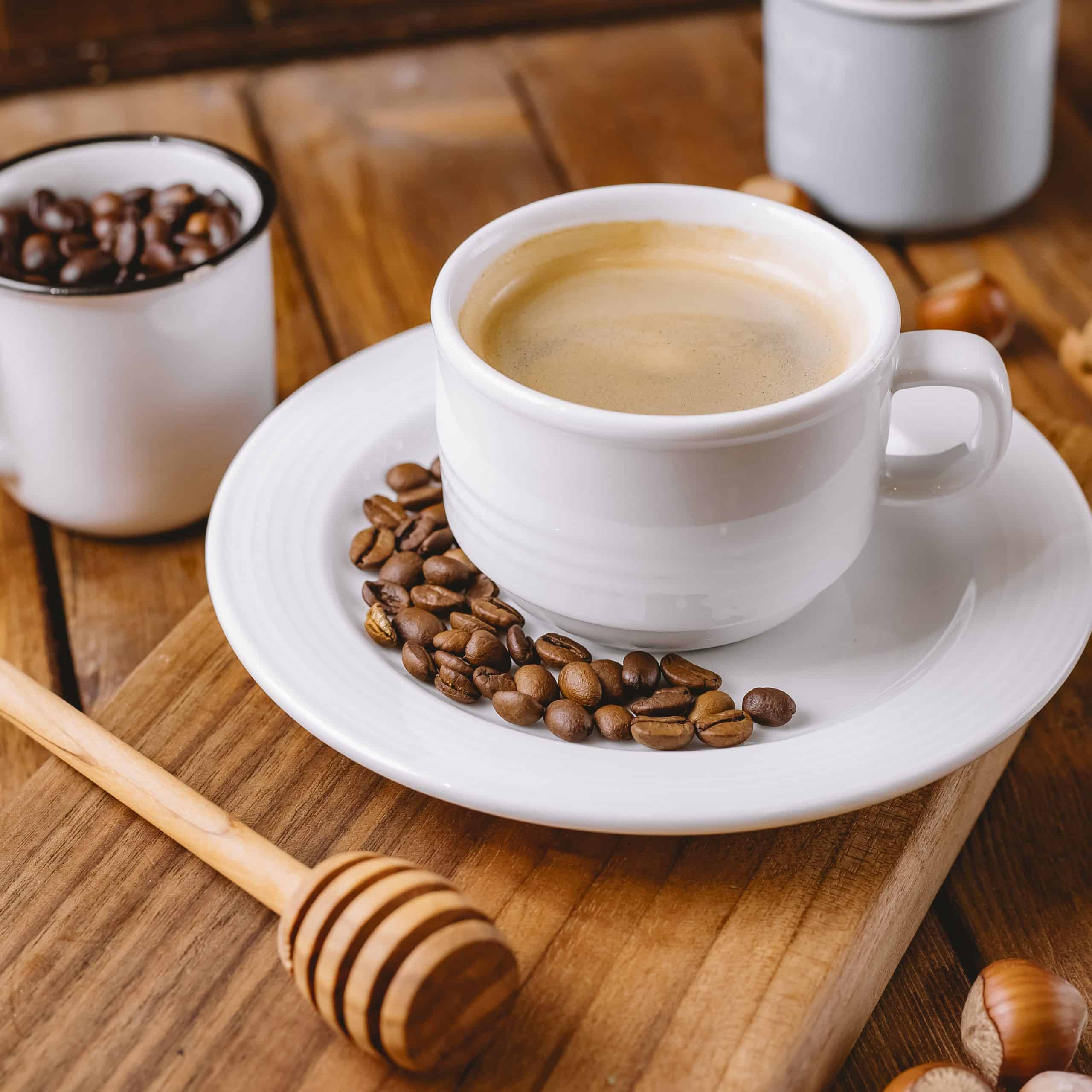close up of coffee cup decorated with coffee beans placed on wooden serving board
